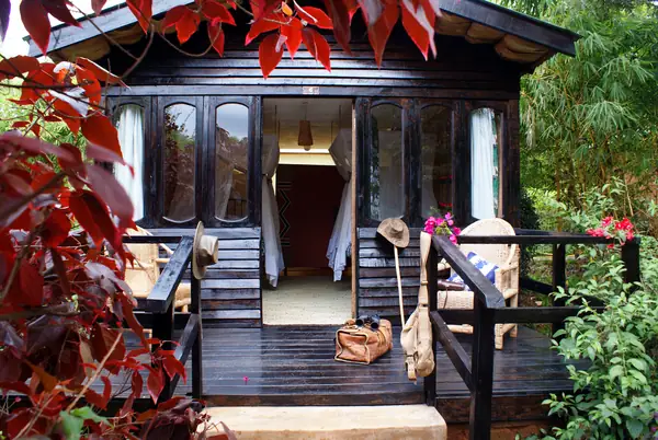 Dark timber chalet with a veranda among red-leaved shrubs